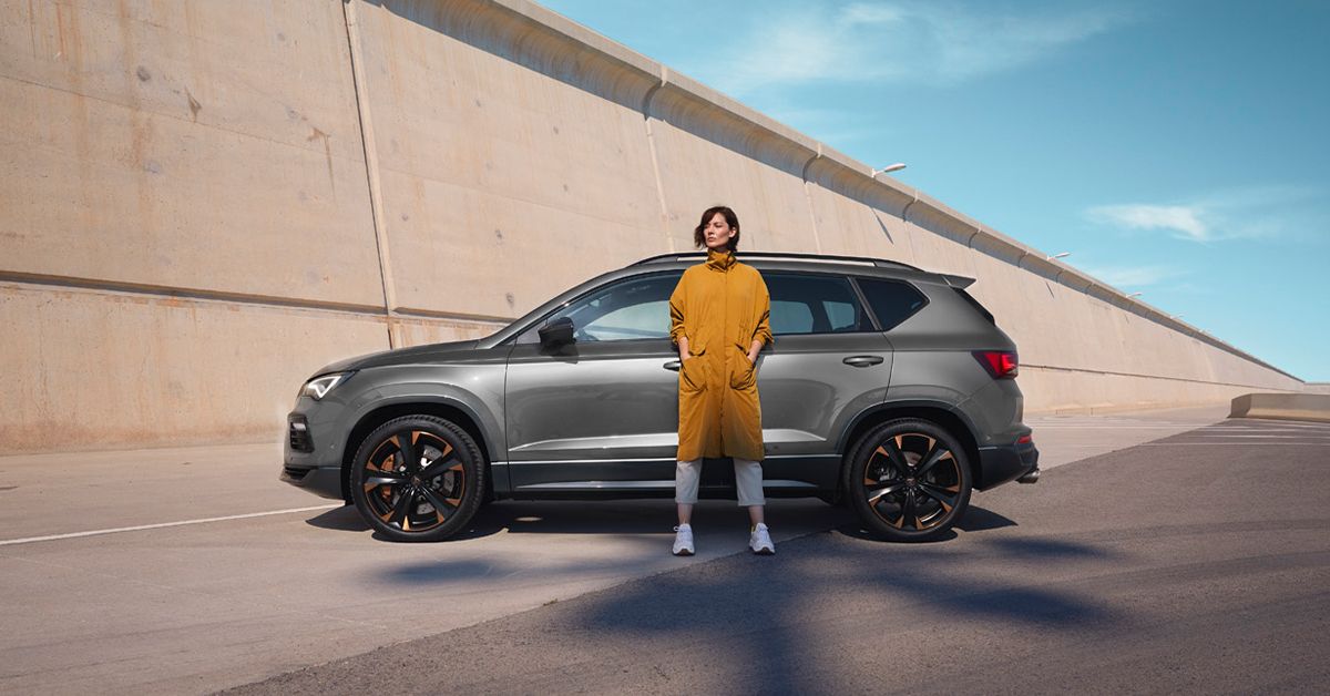 A lady in yellow waiting beside a CUPRA car