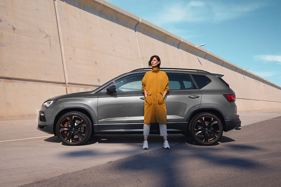 A lady in yellow waiting beside a CUPRA car