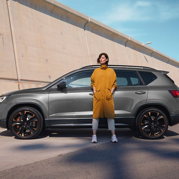 A lady in yellow waiting beside a CUPRA car