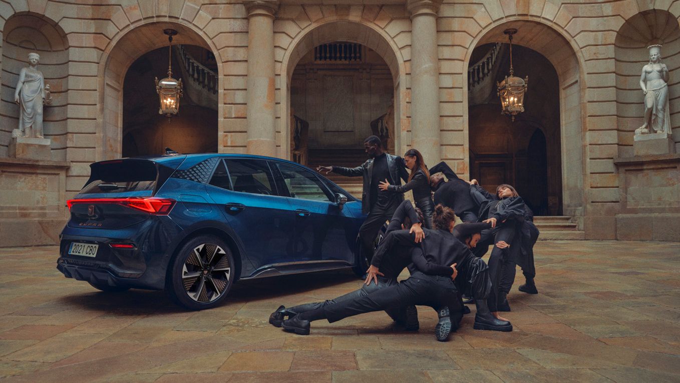 CUPRA Born parked in a courtyard with models posing beside it