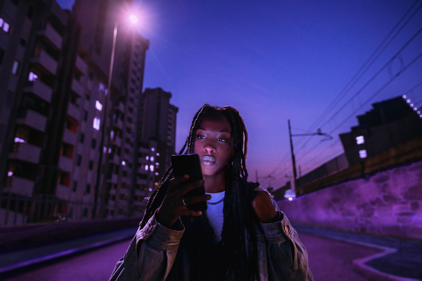 A girl walking while looking at her phone at night