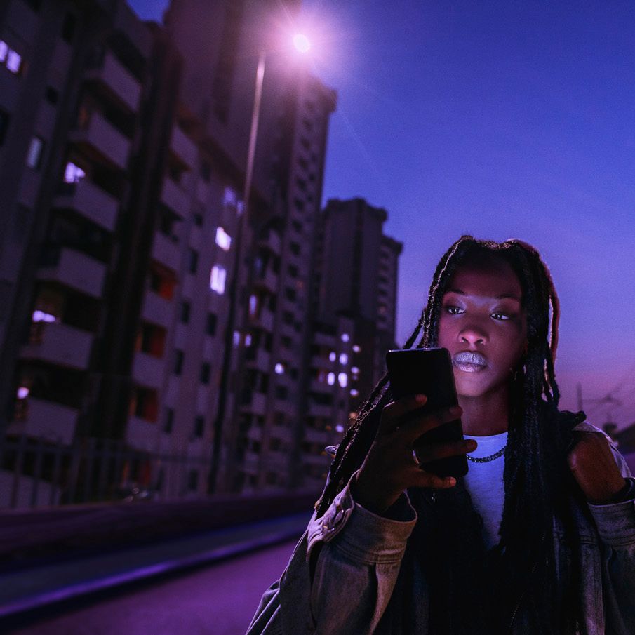 A girl walking while looking at her phone at night