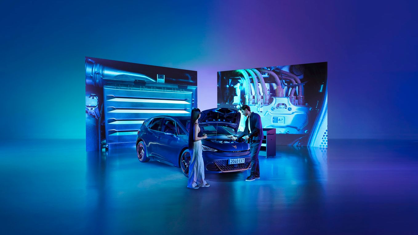 A couple is looking at the engine of a the CUPRA Born with its bonnet open, set against a futuristic backdrop. The background features mechanical imagery and vibrant lighting. 
