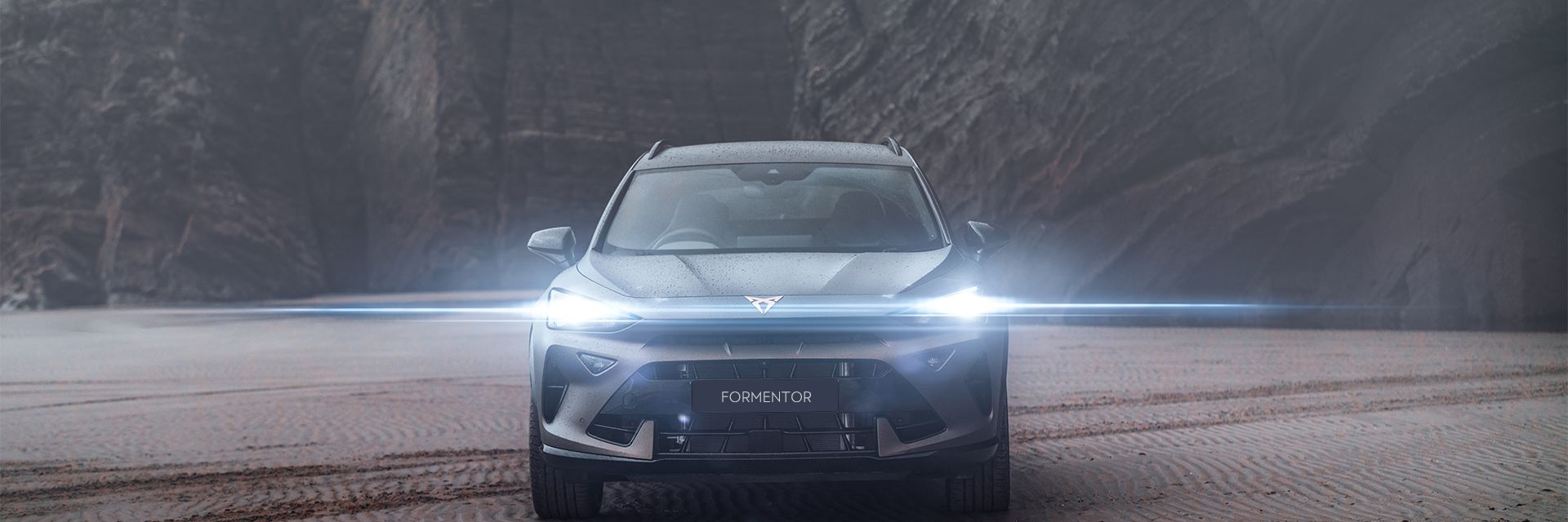 CUPRA Formentor parked in a deserted area with sand and mountain