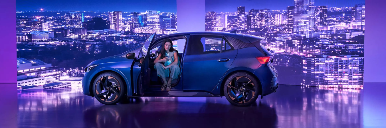 A lady sitting in a CUPRA Born while checking her phone