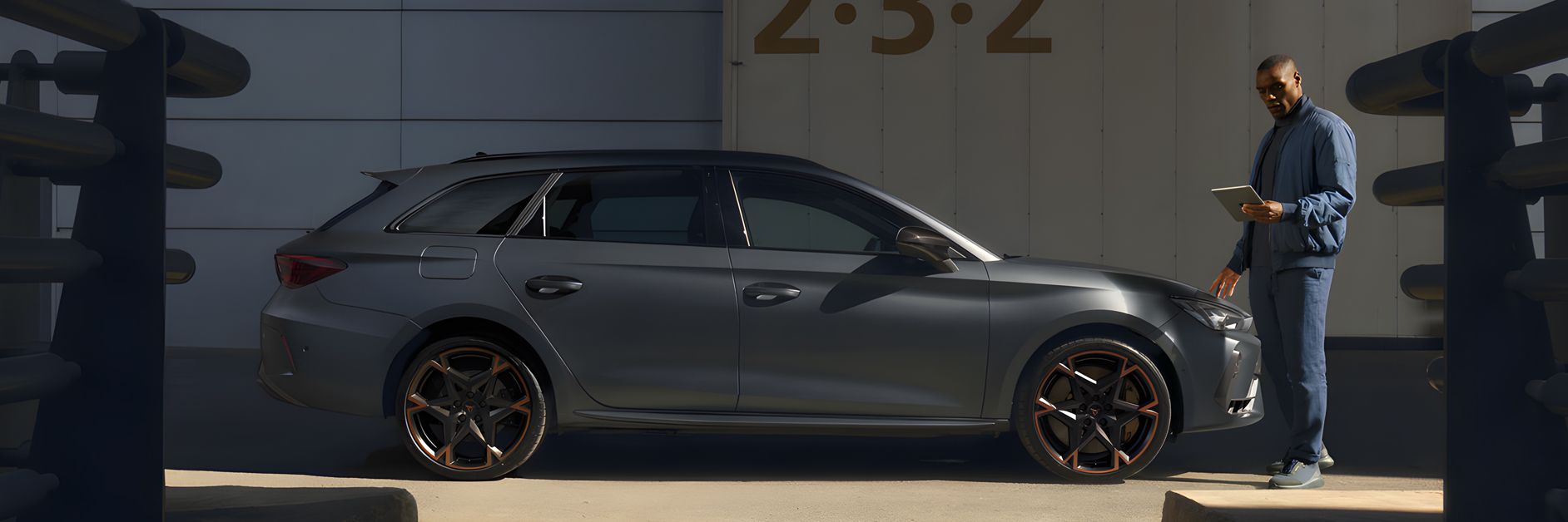 Side view of the CUPRA Leon while a service man is checking on his tablet about the car