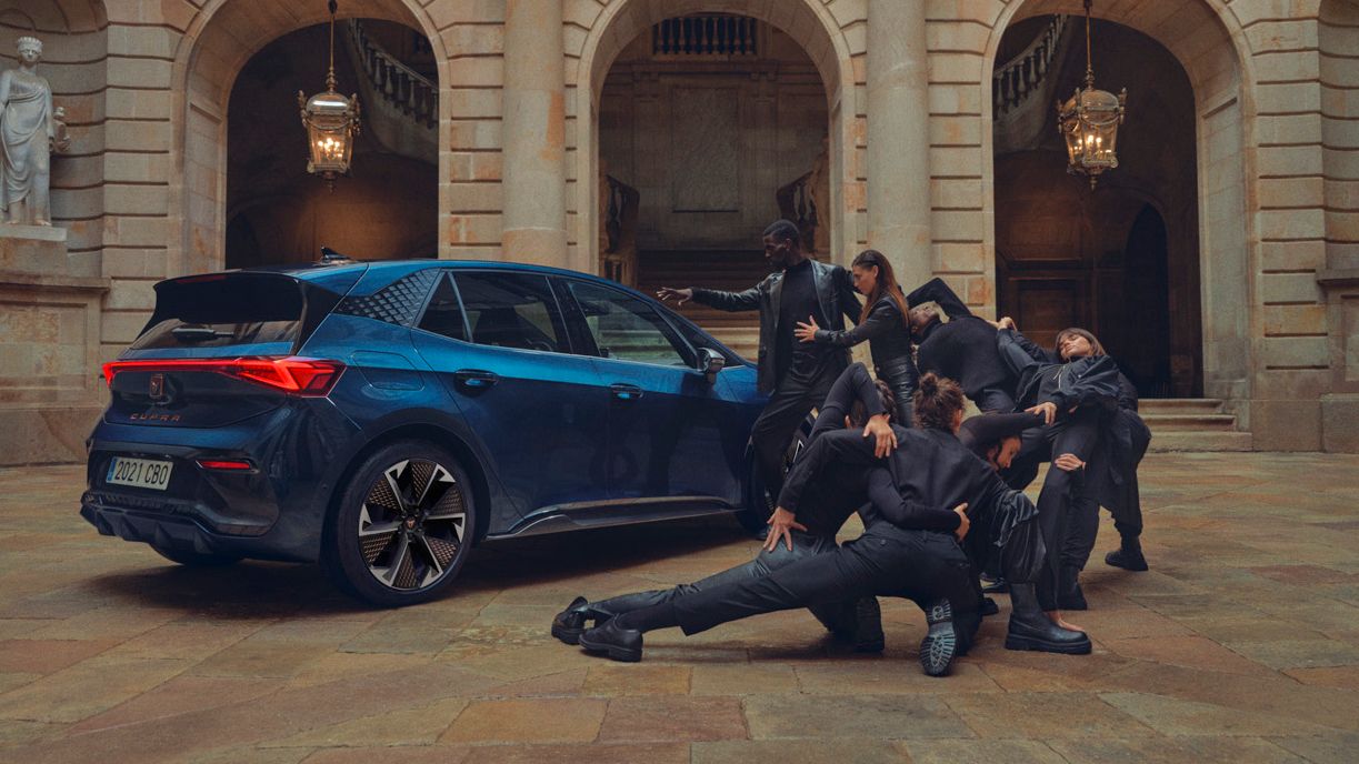 CUPRA Born parked in a courtyard with models posing beside it
