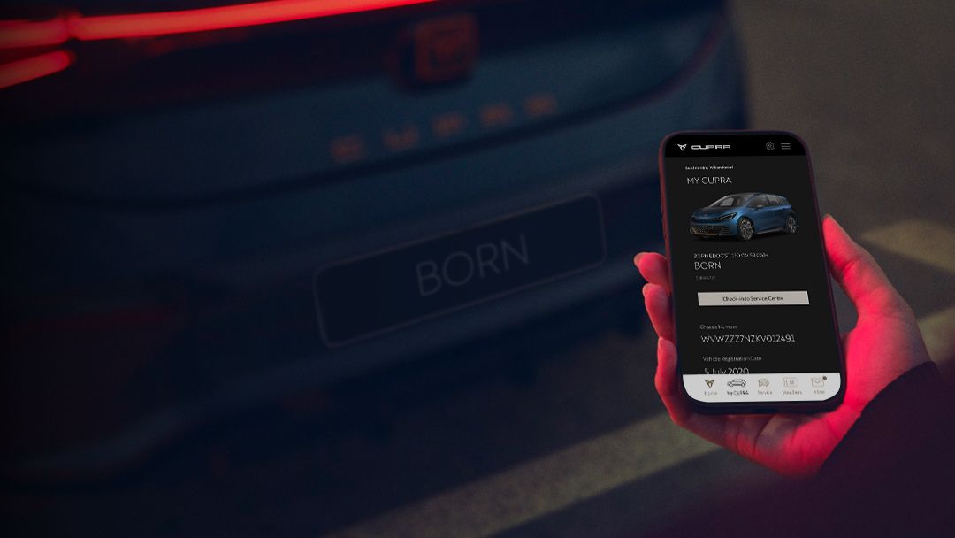 A person holding a phone looking at CUPRA SG app, behind there is a CUPRA Born