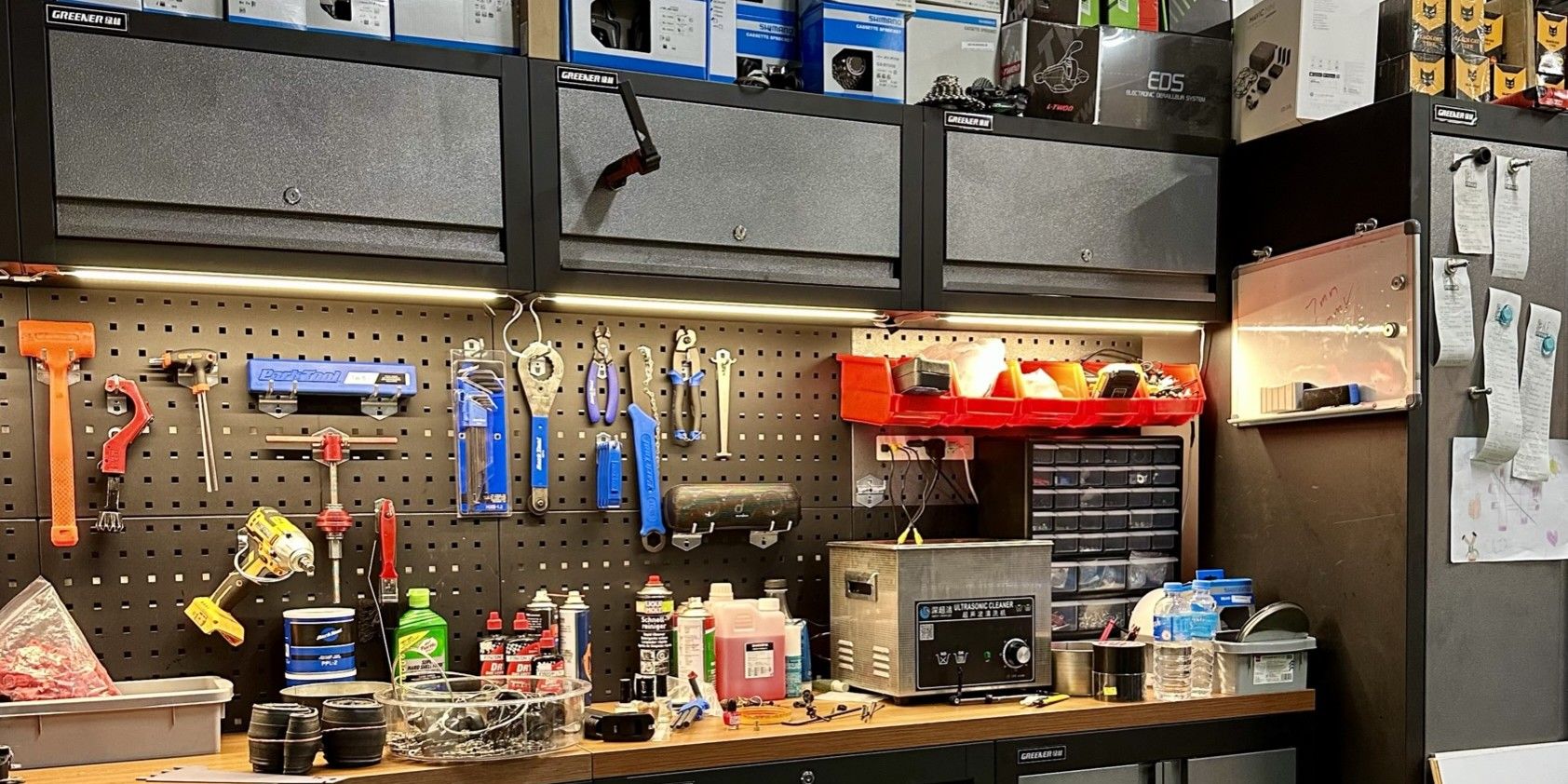 A well-organised workshop with various tools hanging on a pegboard above a wooden workbench