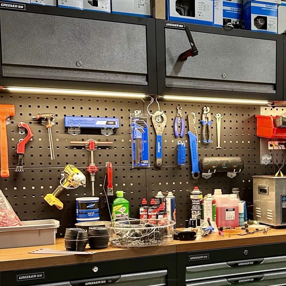 A well-organised workshop with various tools hanging on a pegboard above a wooden workbench