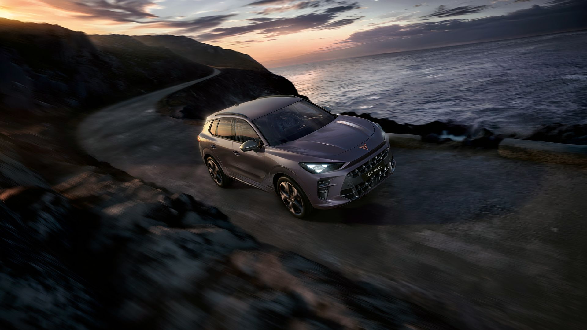 CUPRA Terramar going up hill by the coast of a nearby beach with evening sunset view