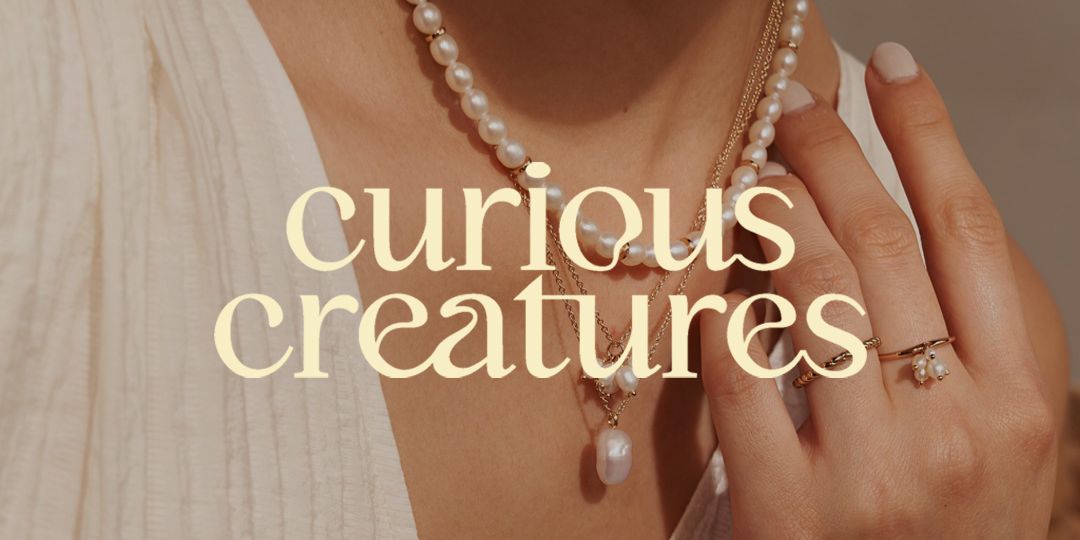 Curious Creatures logo with background of lady's hands and neck with it's brand jewelries 