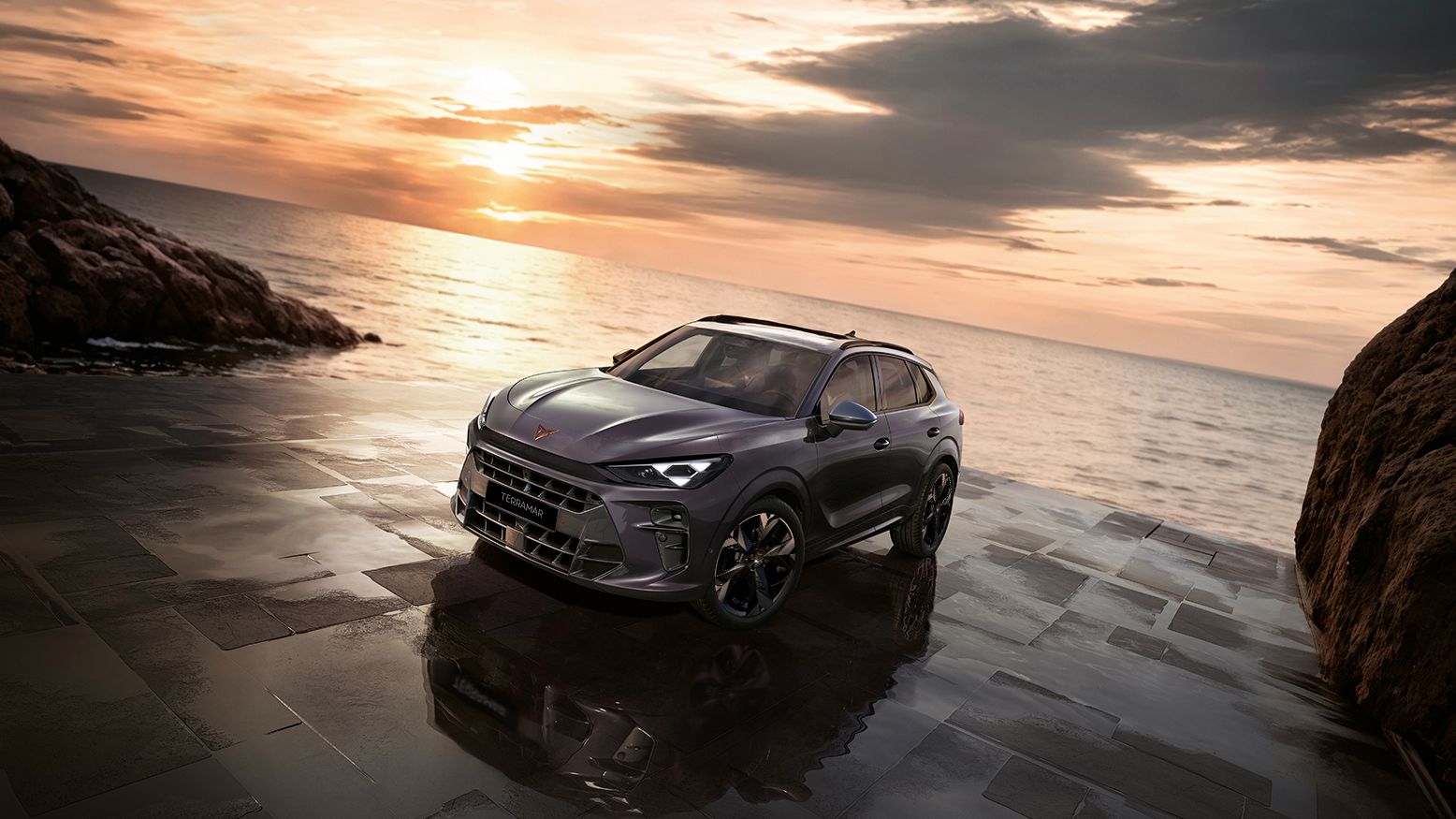 CUPRA Terramar parked at the side of the ocean with the back facing a orange sunset